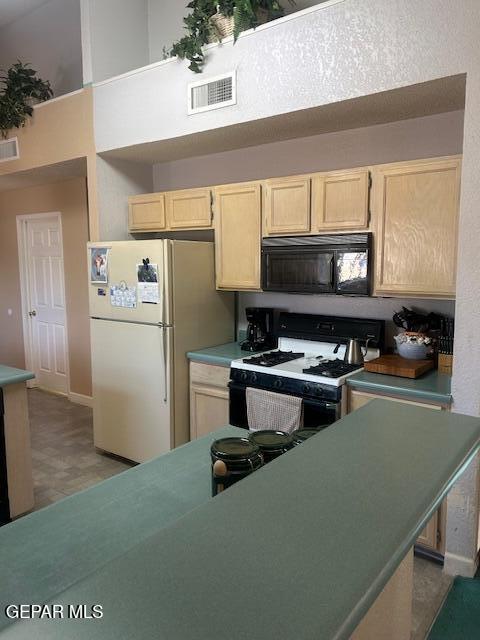 kitchen featuring visible vents, a high ceiling, light brown cabinets, and white appliances