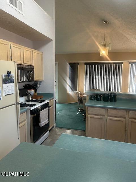 kitchen with range with gas cooktop, visible vents, black microwave, hanging light fixtures, and freestanding refrigerator