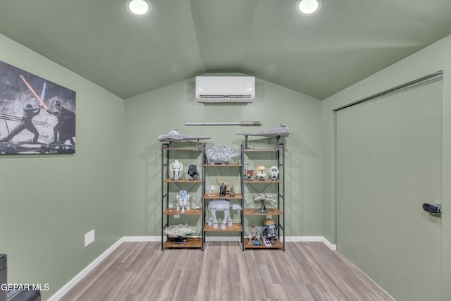 interior space featuring an AC wall unit, baseboards, wood finished floors, and vaulted ceiling