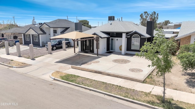 view of front of property with roof with shingles, a chimney, central AC, and stucco siding