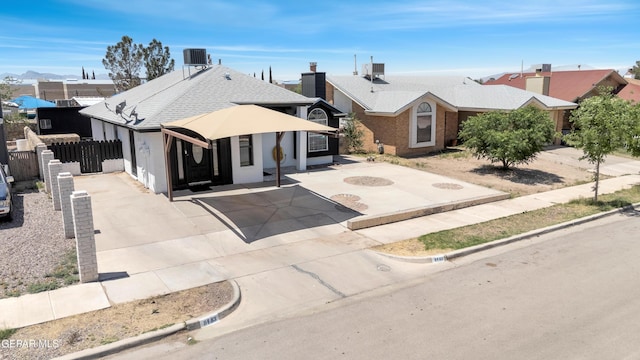 view of front facade featuring central air condition unit, roof with shingles, fence, and driveway