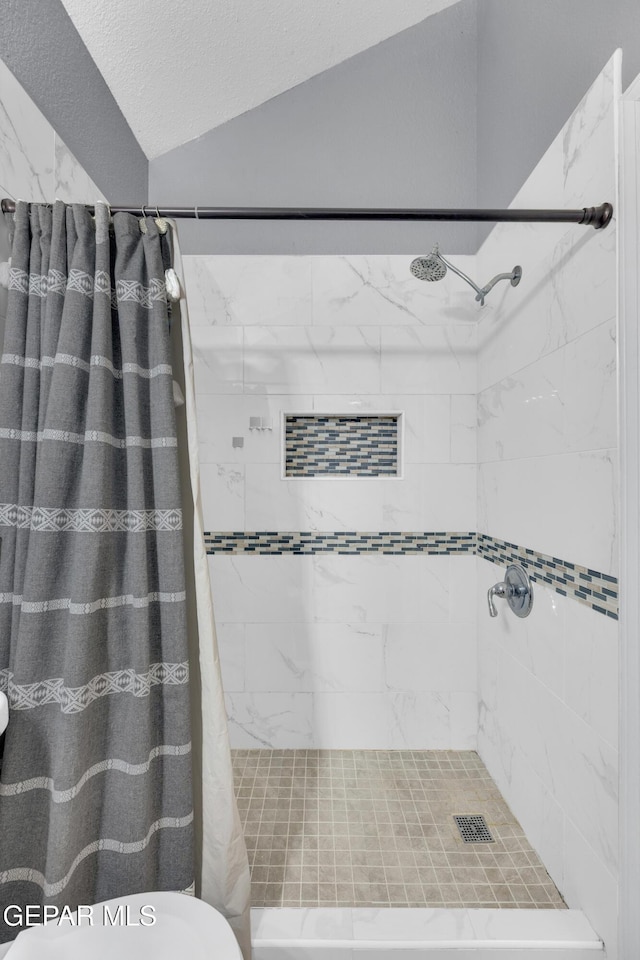 full bath with a stall shower and lofted ceiling
