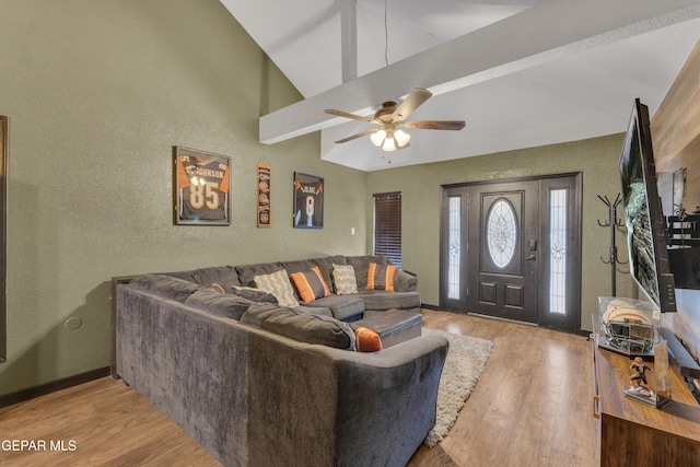 living area with a ceiling fan, wood finished floors, high vaulted ceiling, baseboards, and a textured wall
