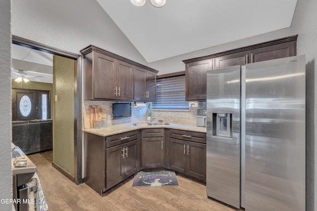kitchen with dark brown cabinetry, vaulted ceiling, a sink, stainless steel fridge with ice dispenser, and light wood finished floors