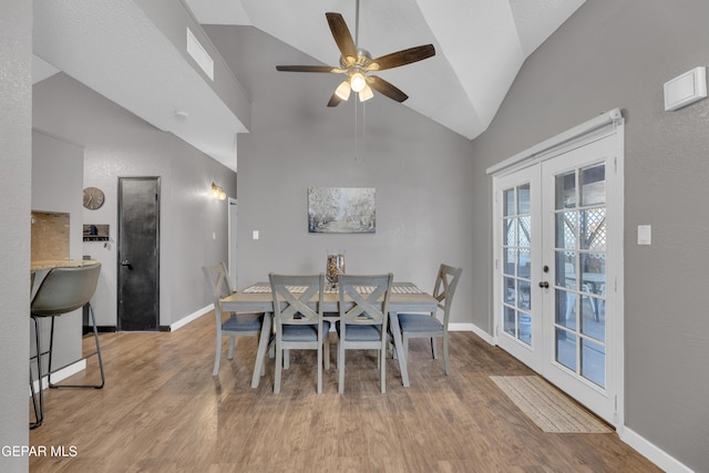 dining space featuring visible vents, lofted ceiling, wood finished floors, ceiling fan, and french doors