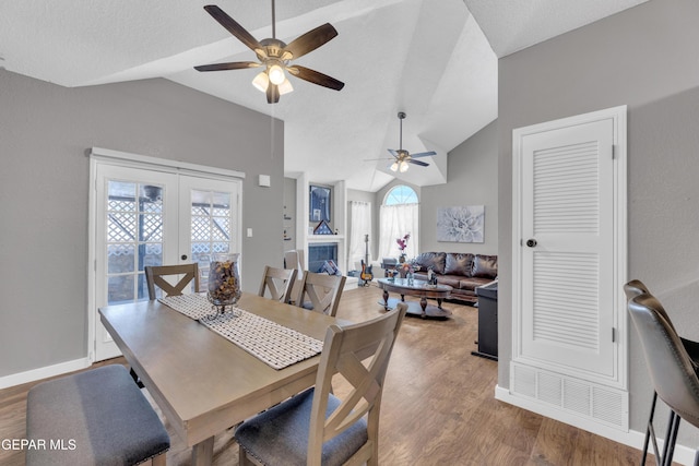 dining room with light wood-type flooring, a ceiling fan, and vaulted ceiling