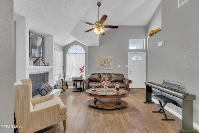 living area featuring ceiling fan, a fireplace, baseboards, wood finished floors, and visible vents