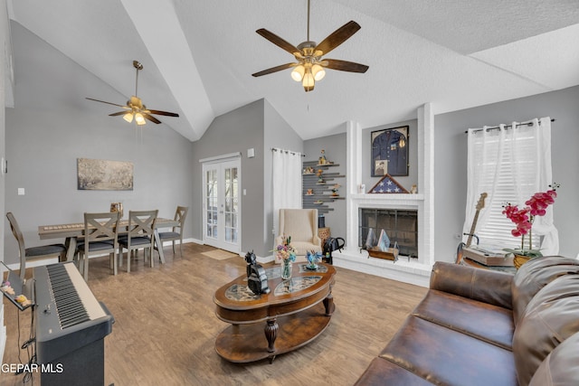 living room featuring a ceiling fan, wood finished floors, lofted ceiling, and a fireplace