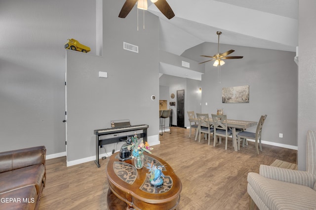 living room featuring ceiling fan, visible vents, wood finished floors, and high vaulted ceiling