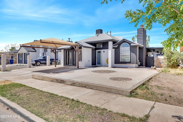 view of front of house featuring fence, central AC unit, a chimney, and driveway