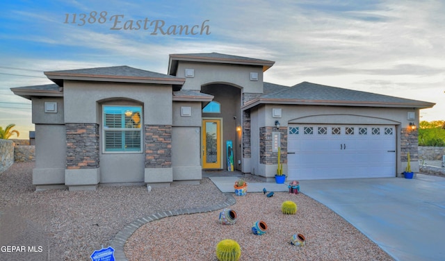 prairie-style house featuring concrete driveway, a garage, stone siding, and stucco siding