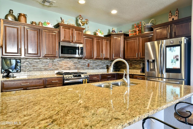 kitchen with backsplash, appliances with stainless steel finishes, a sink, and visible vents