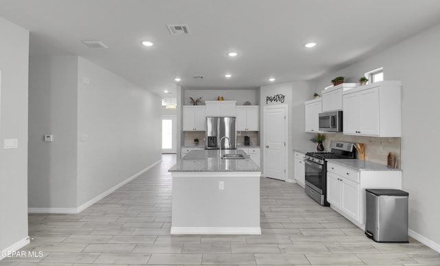 13408 Emerald Glass Dr, Horizon City, TX 79928 - kitchen featuring appliances with stainless steel finishes, baseboards, backsplash, a center island with sink, and recessed lighting