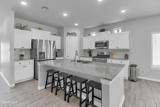 13408 Emerald Glass Dr, Horizon City, TX 79928 - kitchen with appliances with stainless steel finishes, a sink, baseboards, wood finish floors, and a breakfast bar area