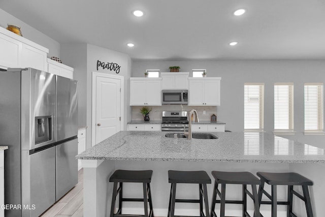 13408 Emerald Glass Dr, Horizon City, TX 79928 - kitchen with stainless steel appliances, a sink, a breakfast bar, recessed lighting, and white cabinetry
