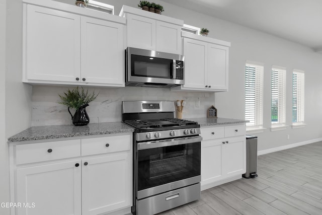 13408 Emerald Glass Dr, Horizon City, TX 79928 - kitchen with appliances with stainless steel finishes, backsplash, white cabinets, light stone countertops, and baseboards