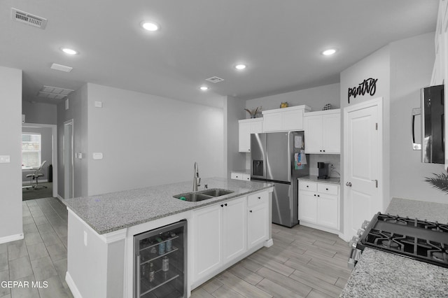 13408 Emerald Glass Dr, Horizon City, TX 79928 - kitchen featuring a sink, beverage cooler, appliances with stainless steel finishes, wood tiled floors, and white cabinets