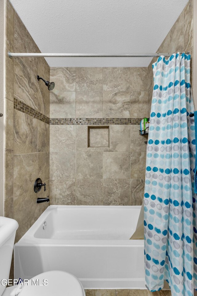 full bathroom with shower / bath combo, toilet, and a textured ceiling