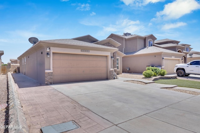 prairie-style home with fence, concrete driveway, an attached garage, stone siding, and stucco siding