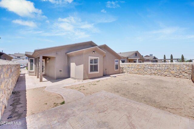 rear view of property featuring a patio, a fenced backyard, and stucco siding
