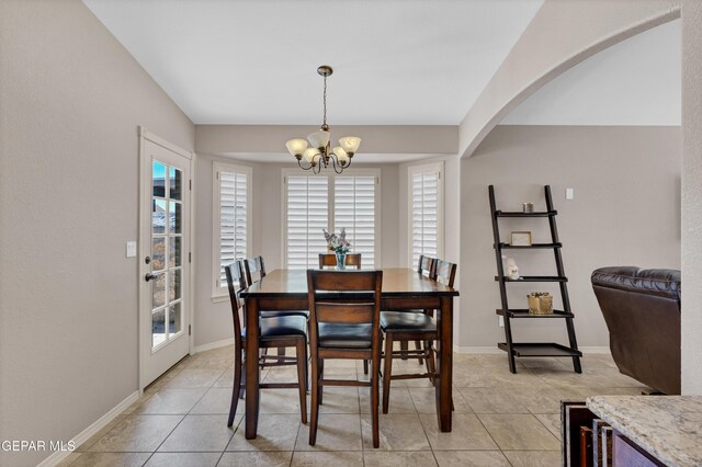 dining room with light tile patterned floors, arched walkways, baseboards, and a notable chandelier