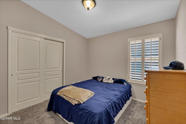 carpeted bedroom with a closet, baseboards, and vaulted ceiling