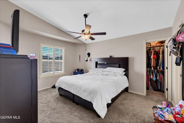 bedroom with carpet flooring, baseboards, vaulted ceiling, and a walk in closet