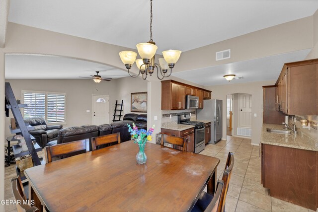 dining room with light tile patterned floors, arched walkways, ceiling fan with notable chandelier, and visible vents