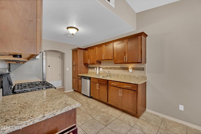 kitchen featuring stainless steel dishwasher, brown cabinetry, and tasteful backsplash