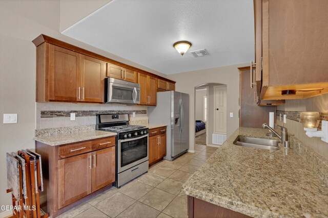 kitchen featuring visible vents, a sink, arched walkways, backsplash, and stainless steel appliances