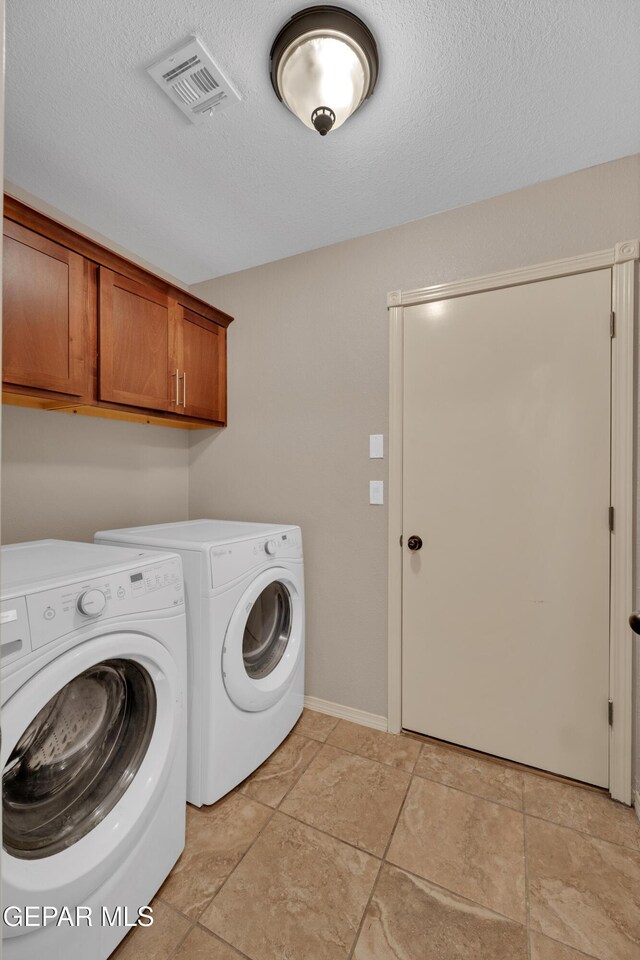 clothes washing area with independent washer and dryer, a textured ceiling, visible vents, and cabinet space