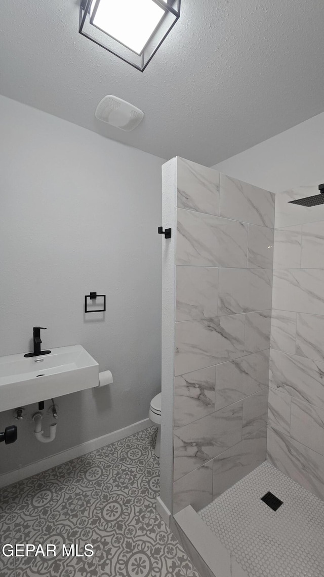 209 Hardesty Pl Unit 1 & 2, El Paso, TX 79905 - bathroom with toilet, a tile shower, a textured ceiling, and baseboards