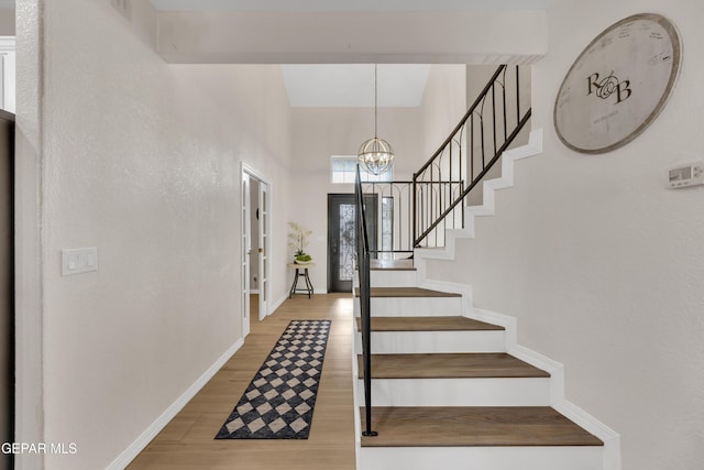 entryway featuring stairway, baseboards, an inviting chandelier, and wood finished floors