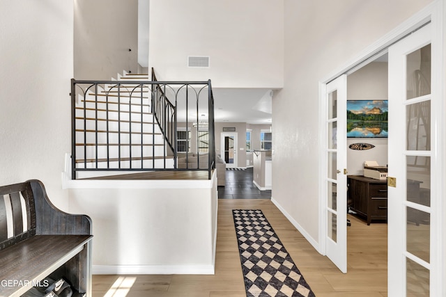 hall with visible vents, stairs, wood finished floors, baseboards, and french doors