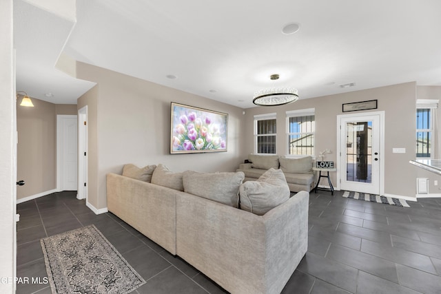 living room featuring dark tile patterned floors, baseboards, and plenty of natural light