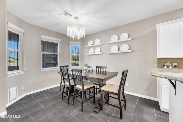 dining room featuring visible vents, baseboards, dark tile patterned flooring, and an inviting chandelier