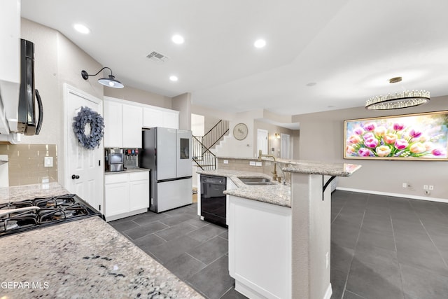 kitchen featuring visible vents, freestanding refrigerator, decorative backsplash, black dishwasher, and a sink
