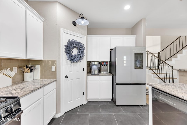 kitchen featuring white cabinets, black appliances, dark tile patterned flooring, and tasteful backsplash