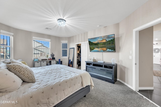 carpeted bedroom featuring visible vents, baseboards, a walk in closet, and a closet