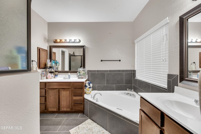 bathroom featuring a bath, a sink, tile patterned floors, and two vanities