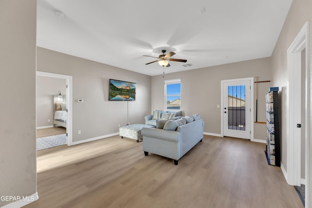 living area featuring light wood-type flooring, baseboards, ceiling fan, and visible vents