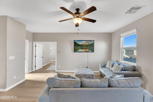 living area featuring a ceiling fan, baseboards, visible vents, and light wood-style floors