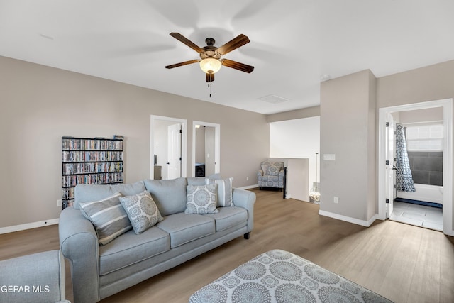 living area featuring a ceiling fan, baseboards, visible vents, and wood finished floors