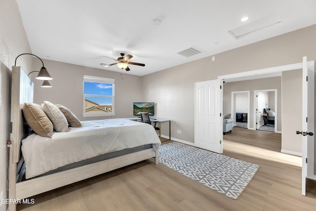 bedroom with ceiling fan, attic access, baseboards, wood finished floors, and visible vents