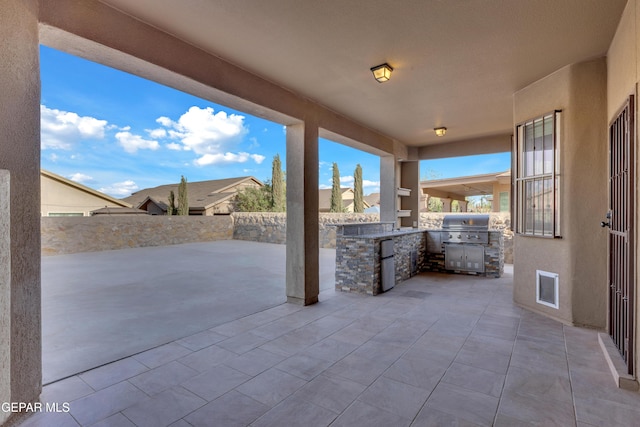 view of patio featuring fence, a grill, and exterior kitchen