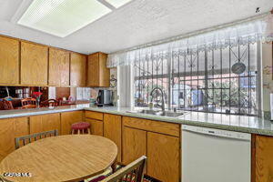 1421 Monte Negro Dr, El Paso, TX 79935 - kitchen featuring brown cabinetry, a sink, dishwasher, and light countertops