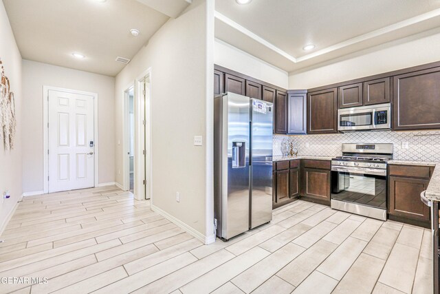 14940 Tierra Escape Ave, El Paso, TX 79938 - kitchen with dark brown cabinets, appliances with stainless steel finishes, light wood-style flooring, baseboards, and decorative backsplash