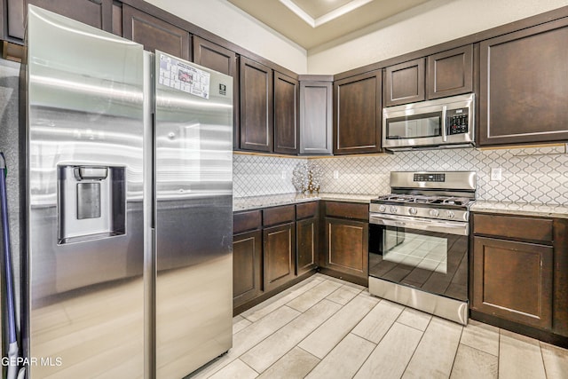 14940 Tierra Escape Ave, El Paso, TX 79938 - kitchen with light stone counters, backsplash, dark brown cabinets, and stainless steel appliances
