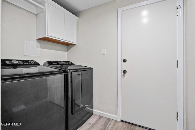 washroom with cabinet space, baseboards, washer and clothes dryer, and light wood-style floors