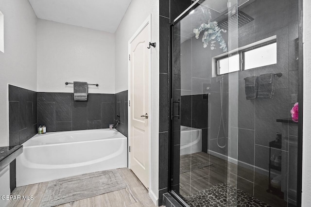 bathroom with a shower stall, wood finished floors, and a bath